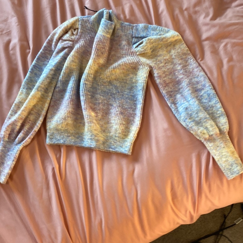 This turtleneck sweater has different variations of pink yellow and blue.
